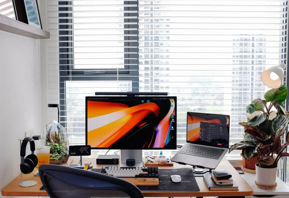 A photographer working at a creative setup with a laptop and Wacom tablet, focused on editing photos indoors.
